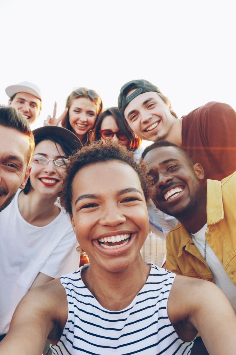 A diverse group of friends taking a joyful selfie outdoors during sunset.